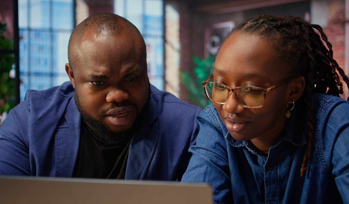 Black man and woman creating a report with online data from archived files, improving their skills and achieving career independence. Remote workers solving daily tasks. Camera A.